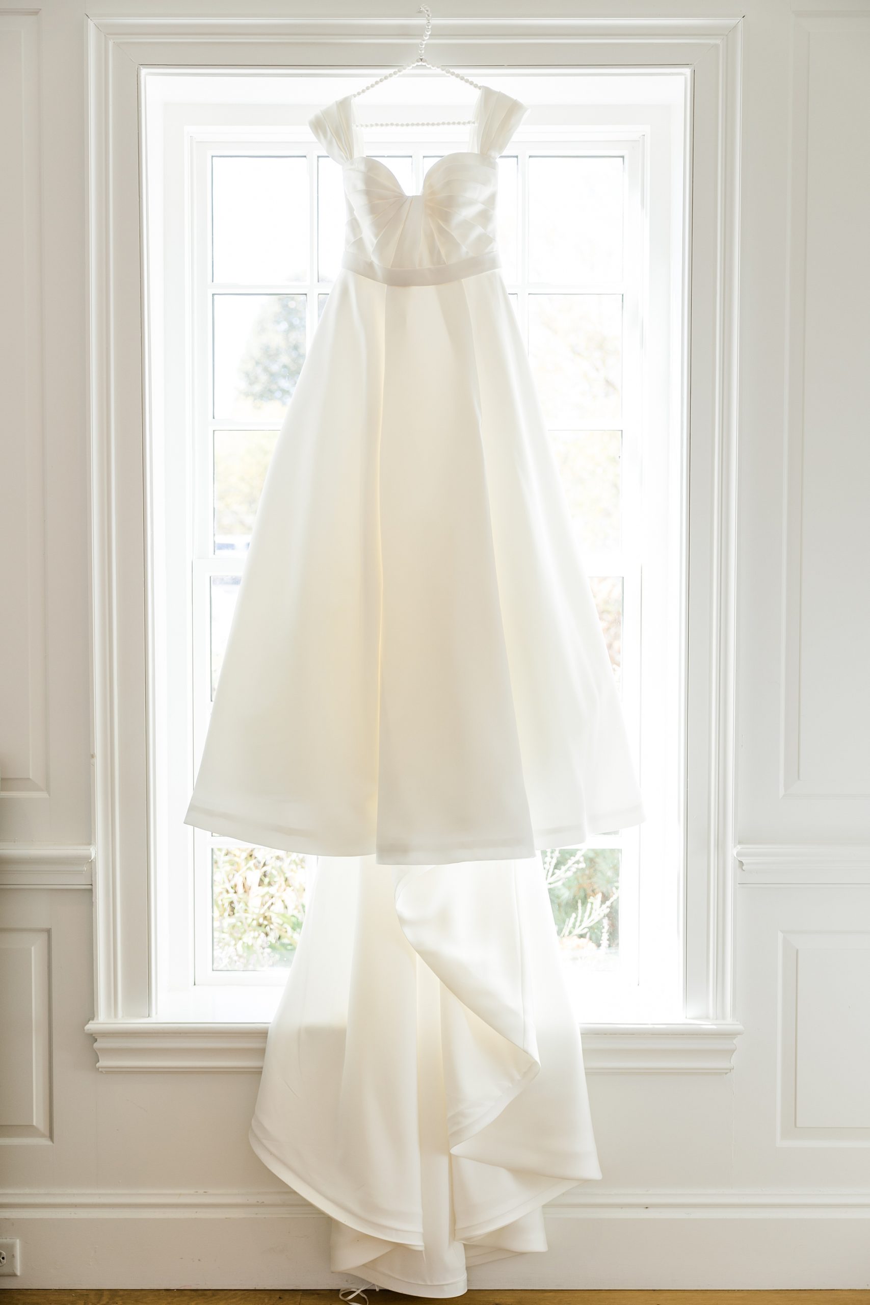 wedding dress hangs from window