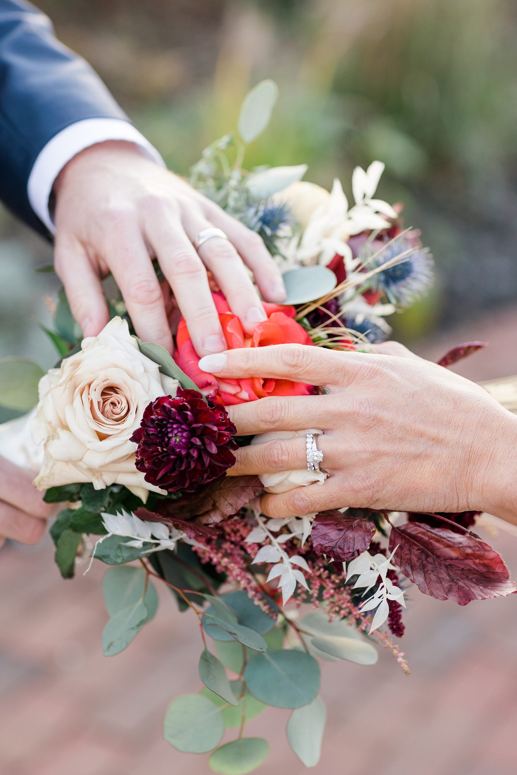 bride and groom put hands on bouquet