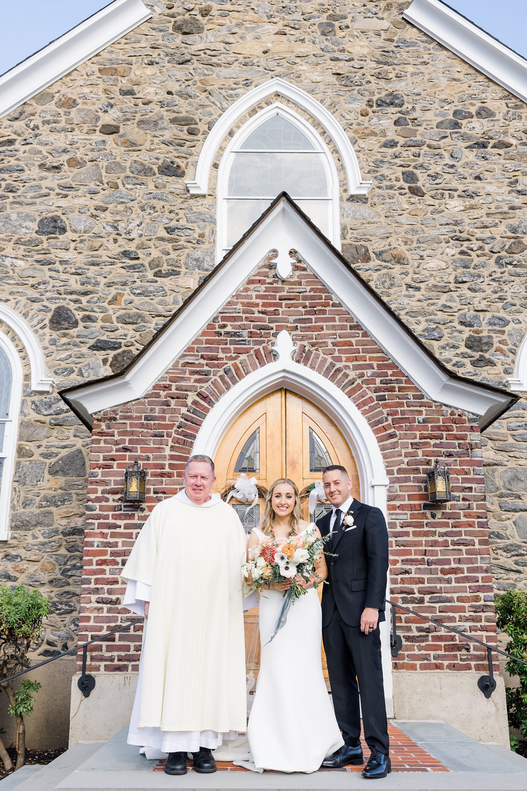 bride and groom with officiant outside church