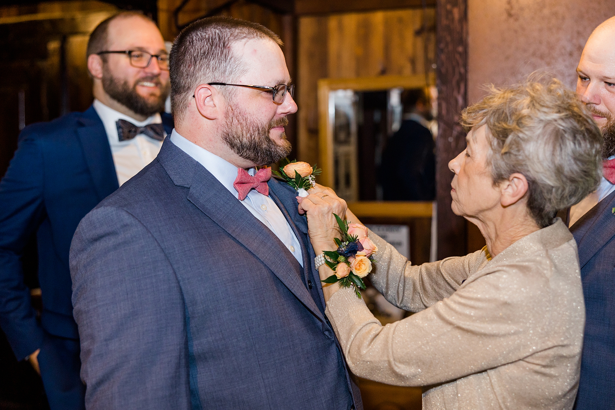 mother pins boutonniere on groom 