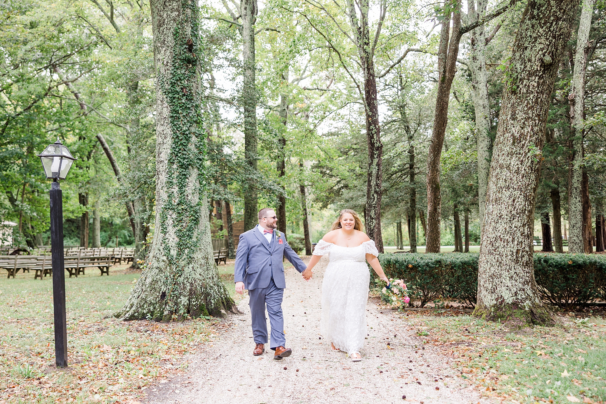bride and groom hold hands as they walk down path in NJ