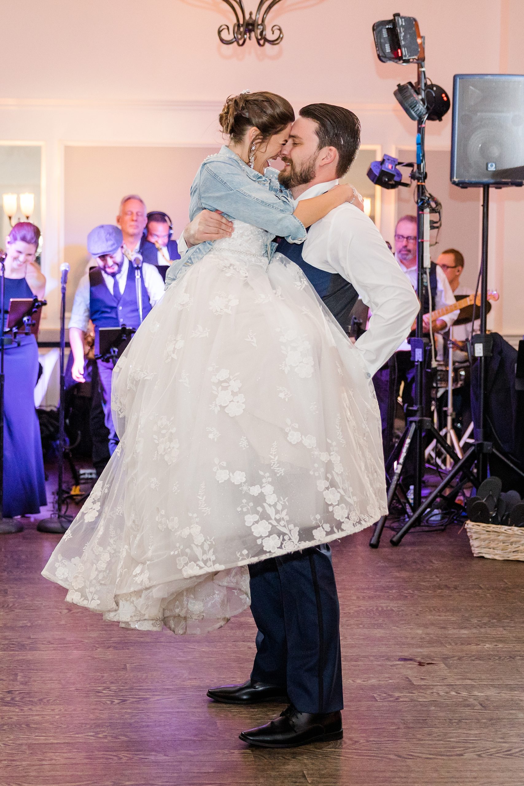 groom holds bride in arms on the dance floor