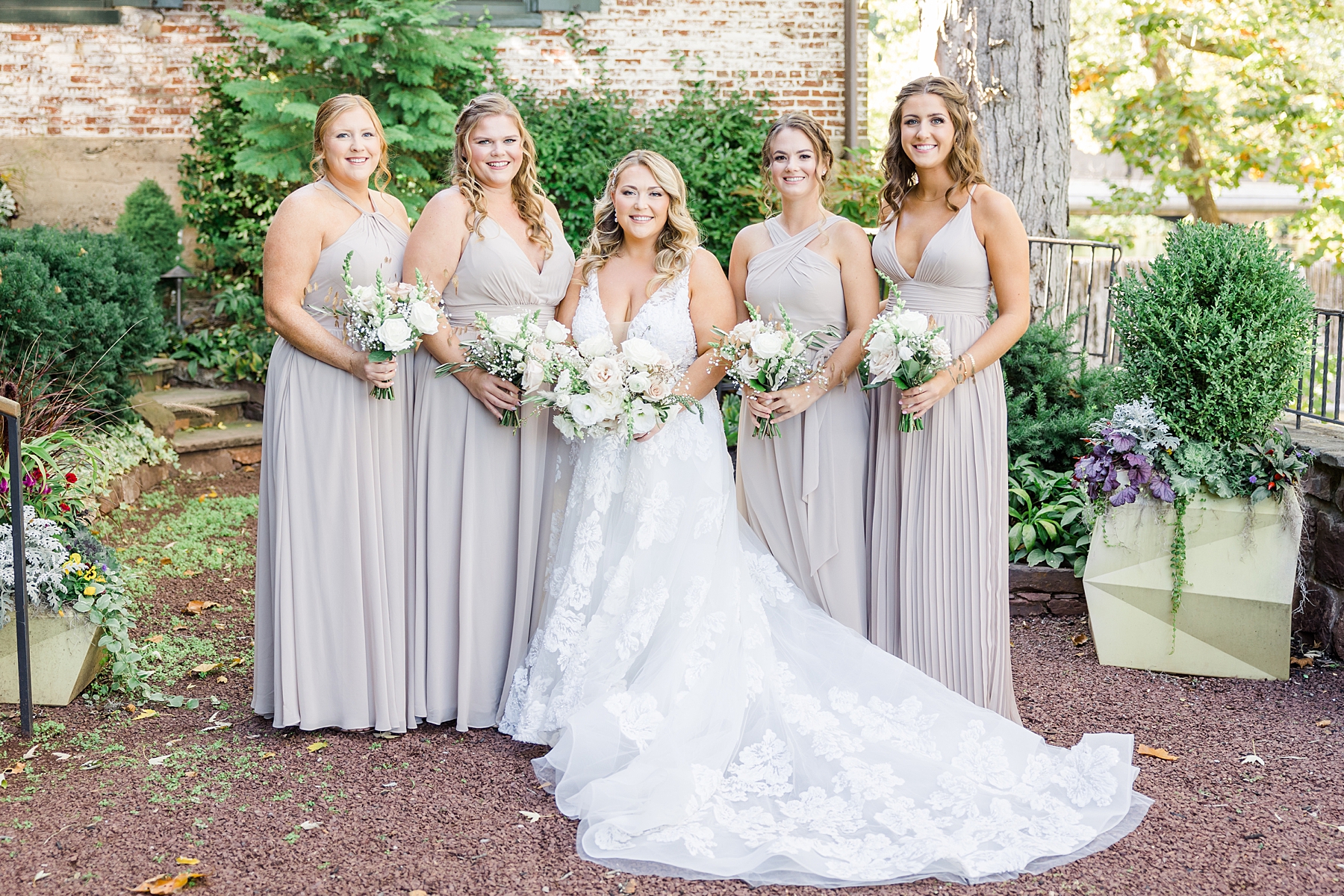 bride with bridesmaids in taupe dresses holding bouquets 