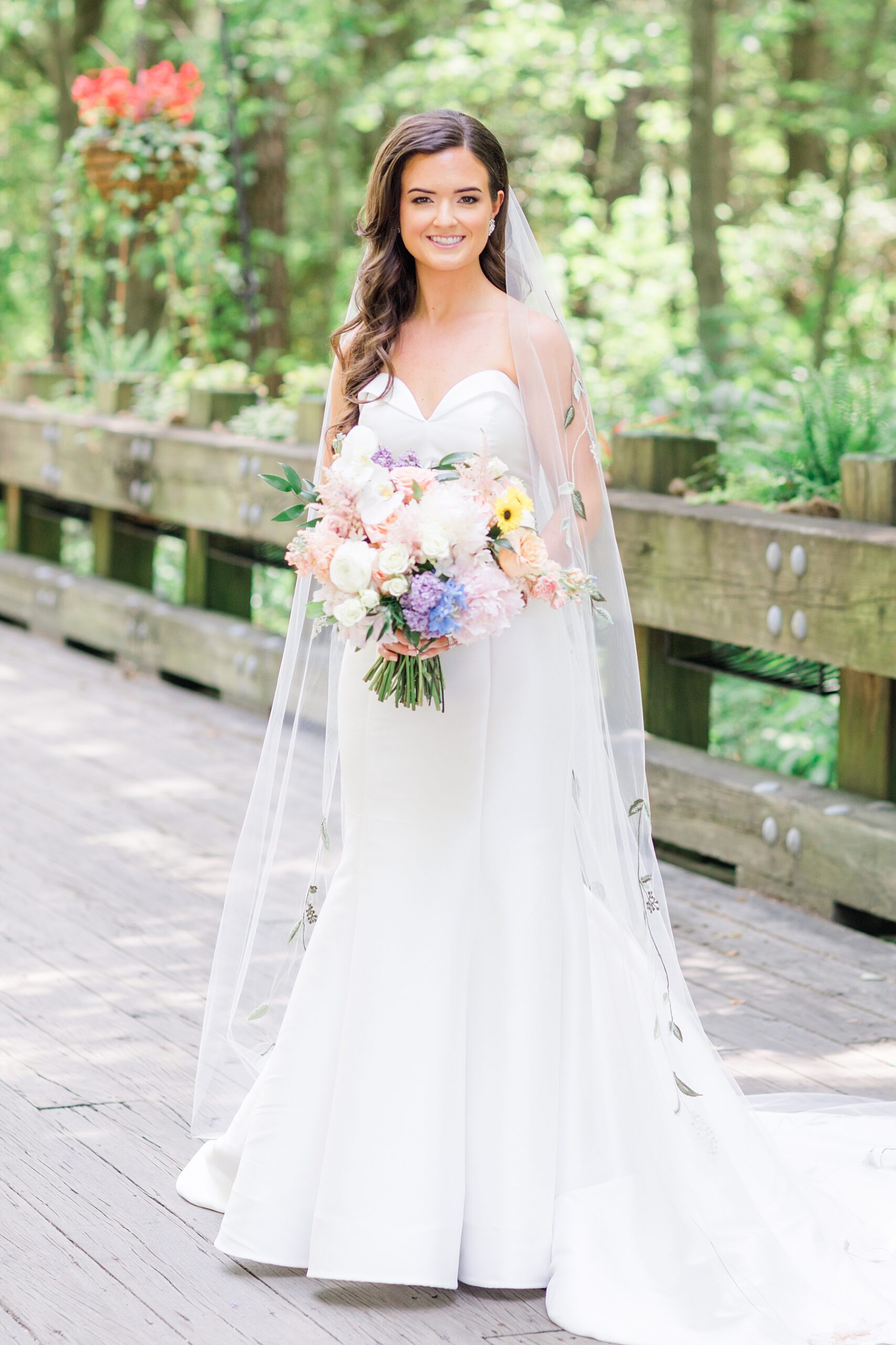 bride on wooden bridge holding garden inspired wedding bouquet 