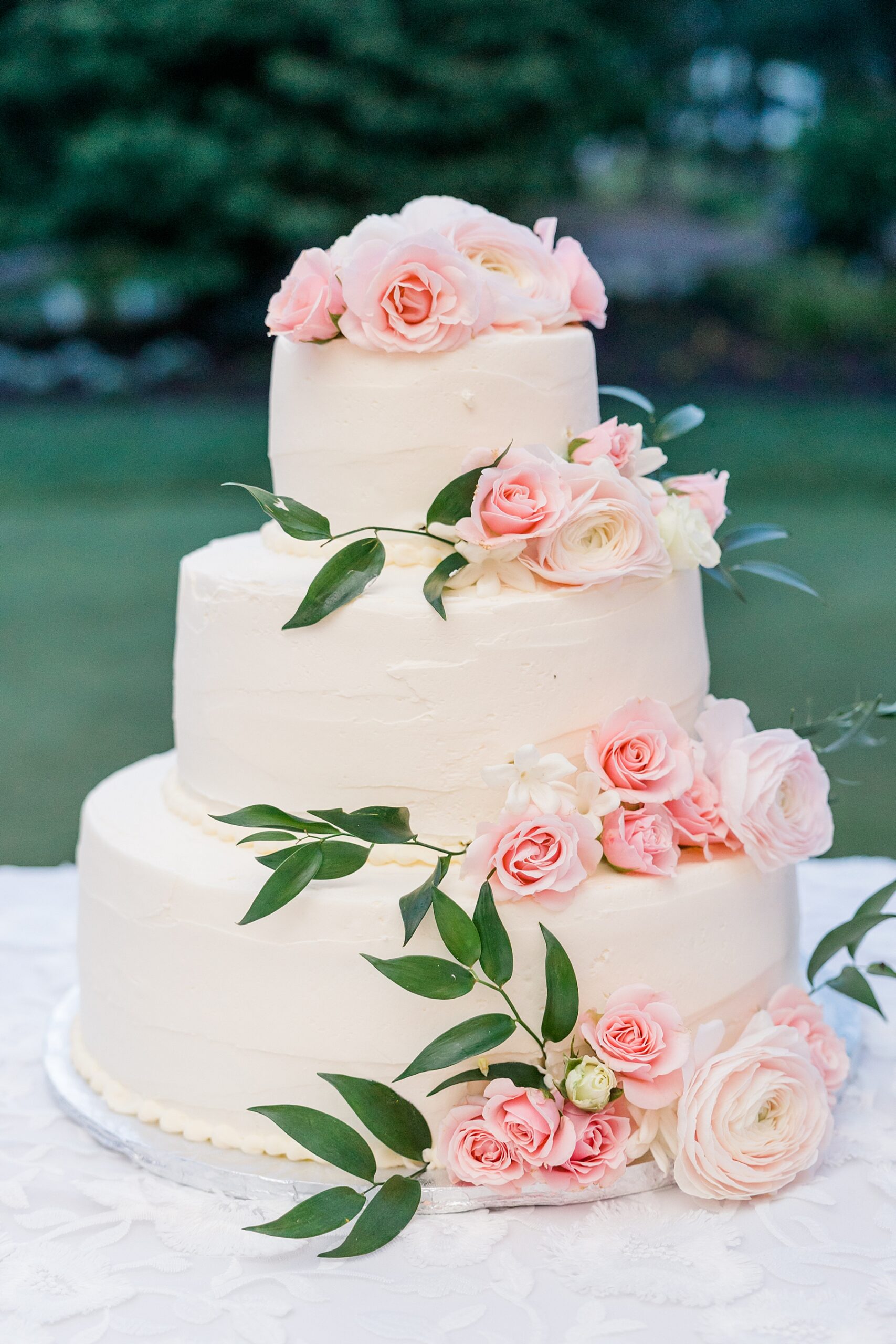 three tired wedding cake with pink flowers and greenery 