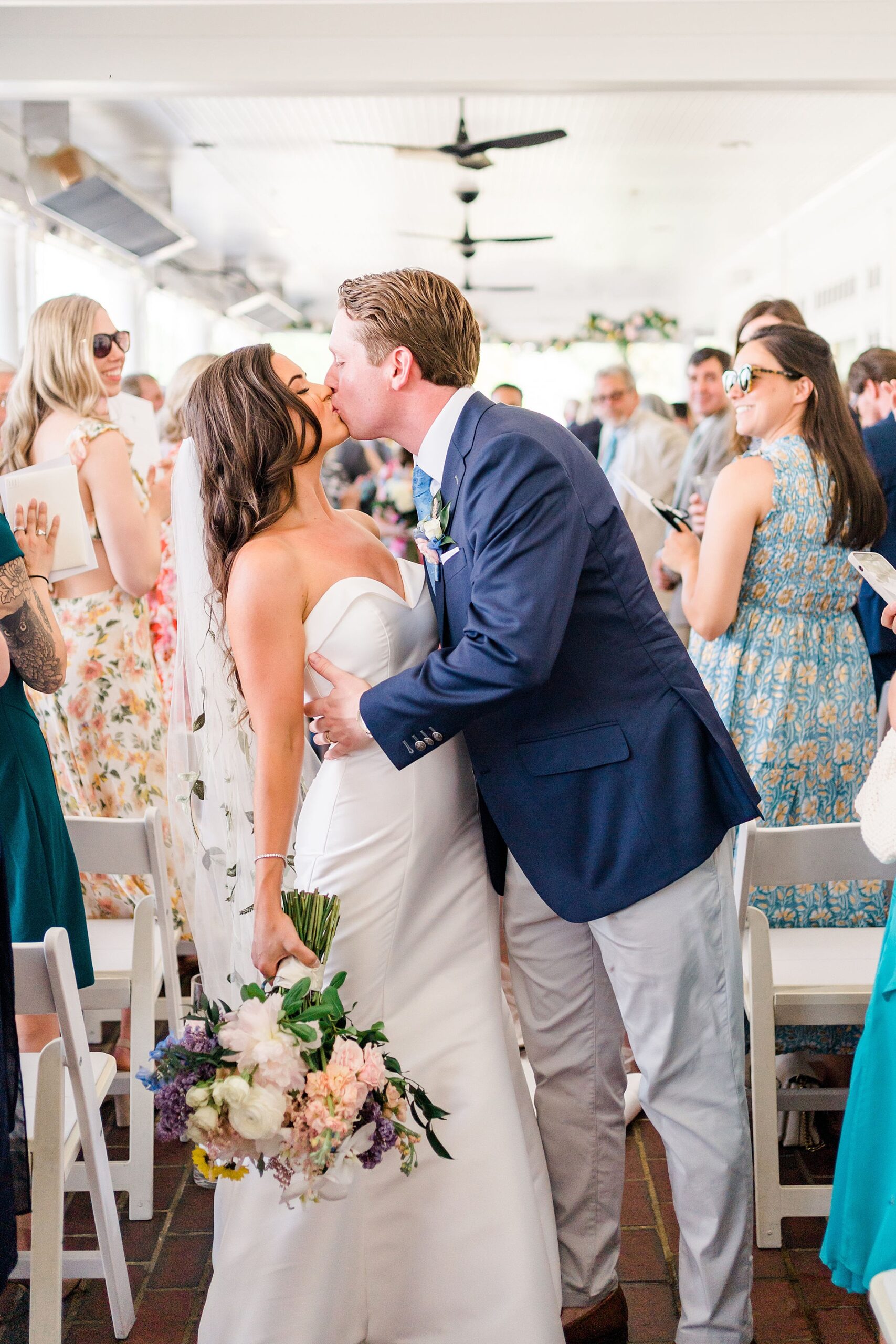 newlyweds kiss as they walk down the aisle together as husband and wife
