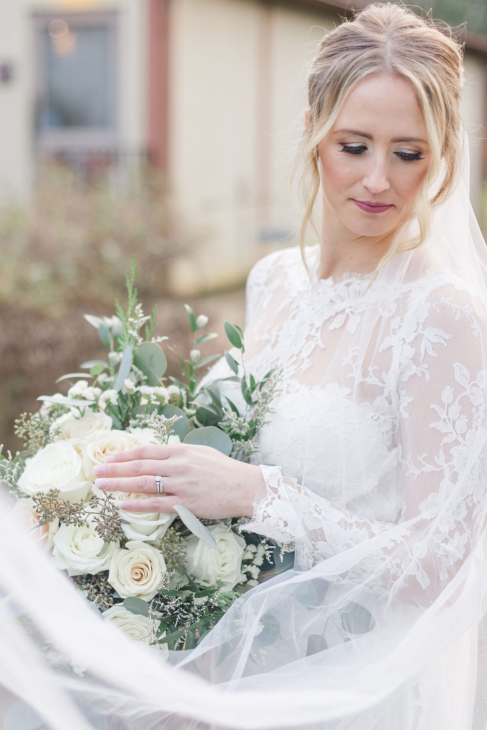 bride in long sleeve wedding dress holding classic white bouquet