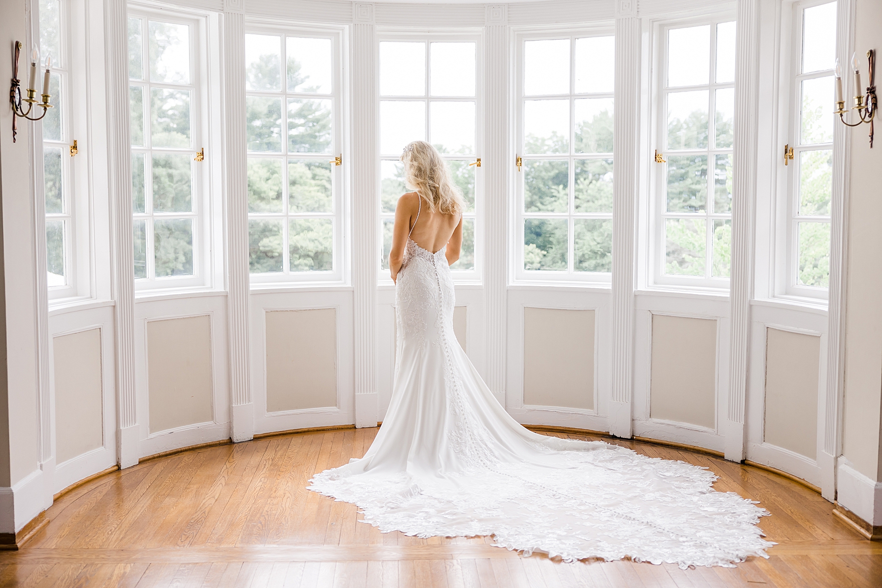 bride looks out windows in bridal suite