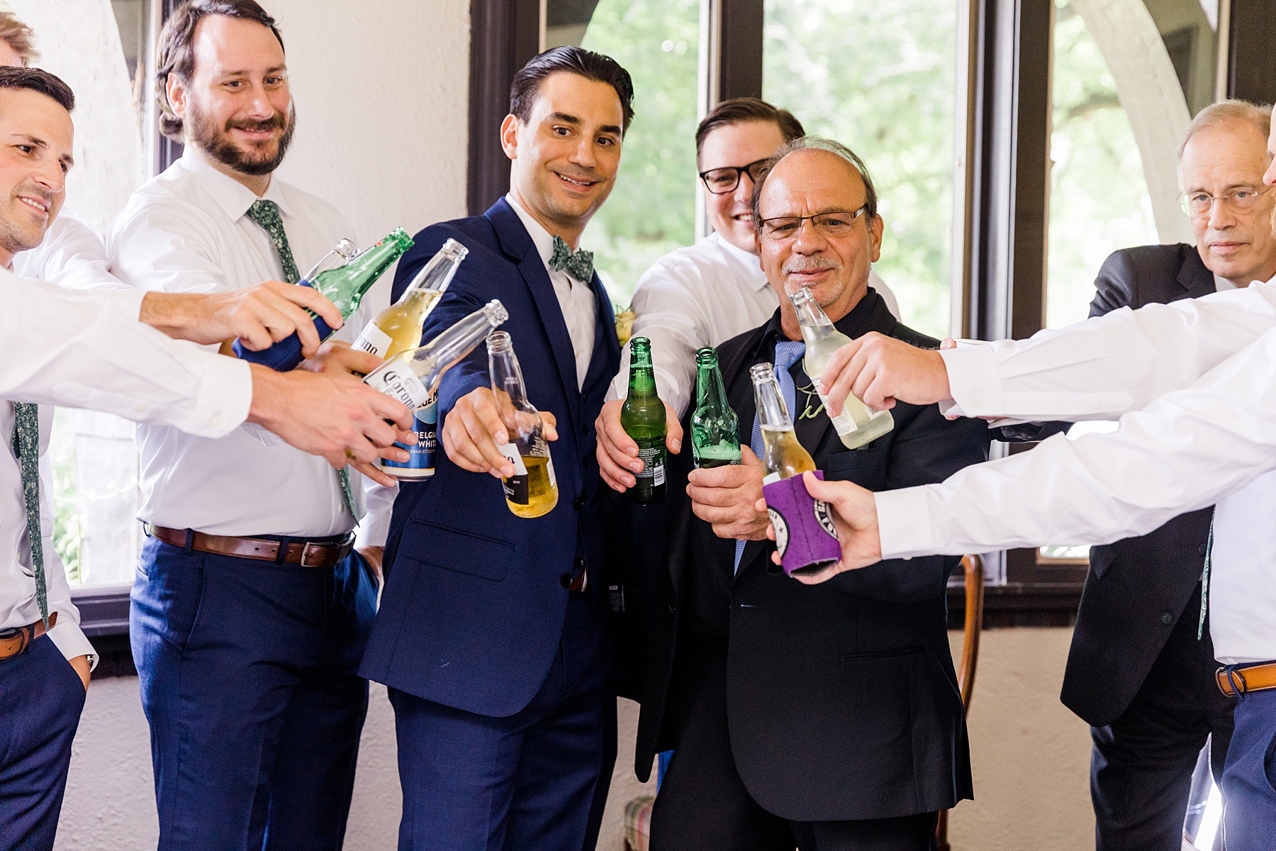groom and groomsmen cheers with a drink before wedding 