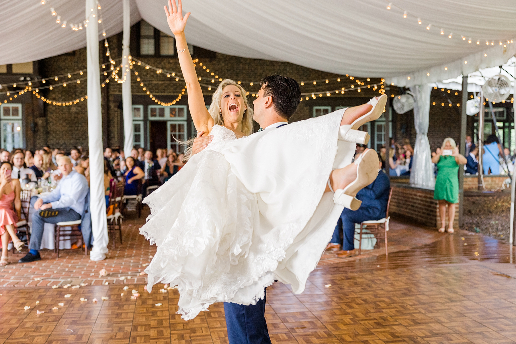 groom picks his bride up on the dance floor 
