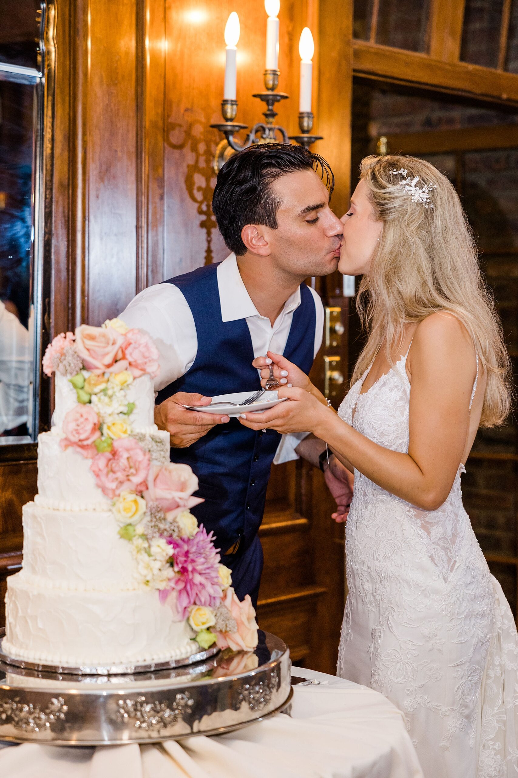 newlyweds kiss by wedding cake 