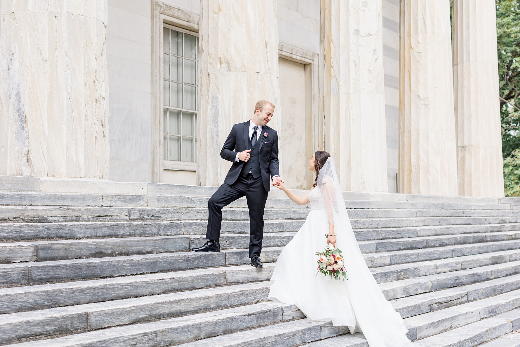 groom leads brode up stairs of historic building in Philadelphia 
