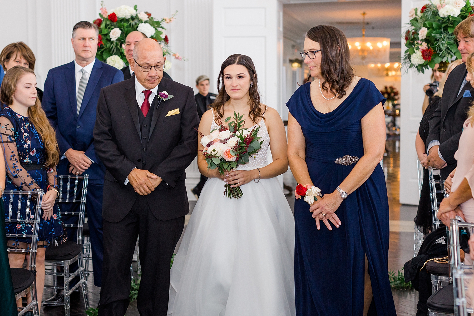bride walks down the aisle with parents