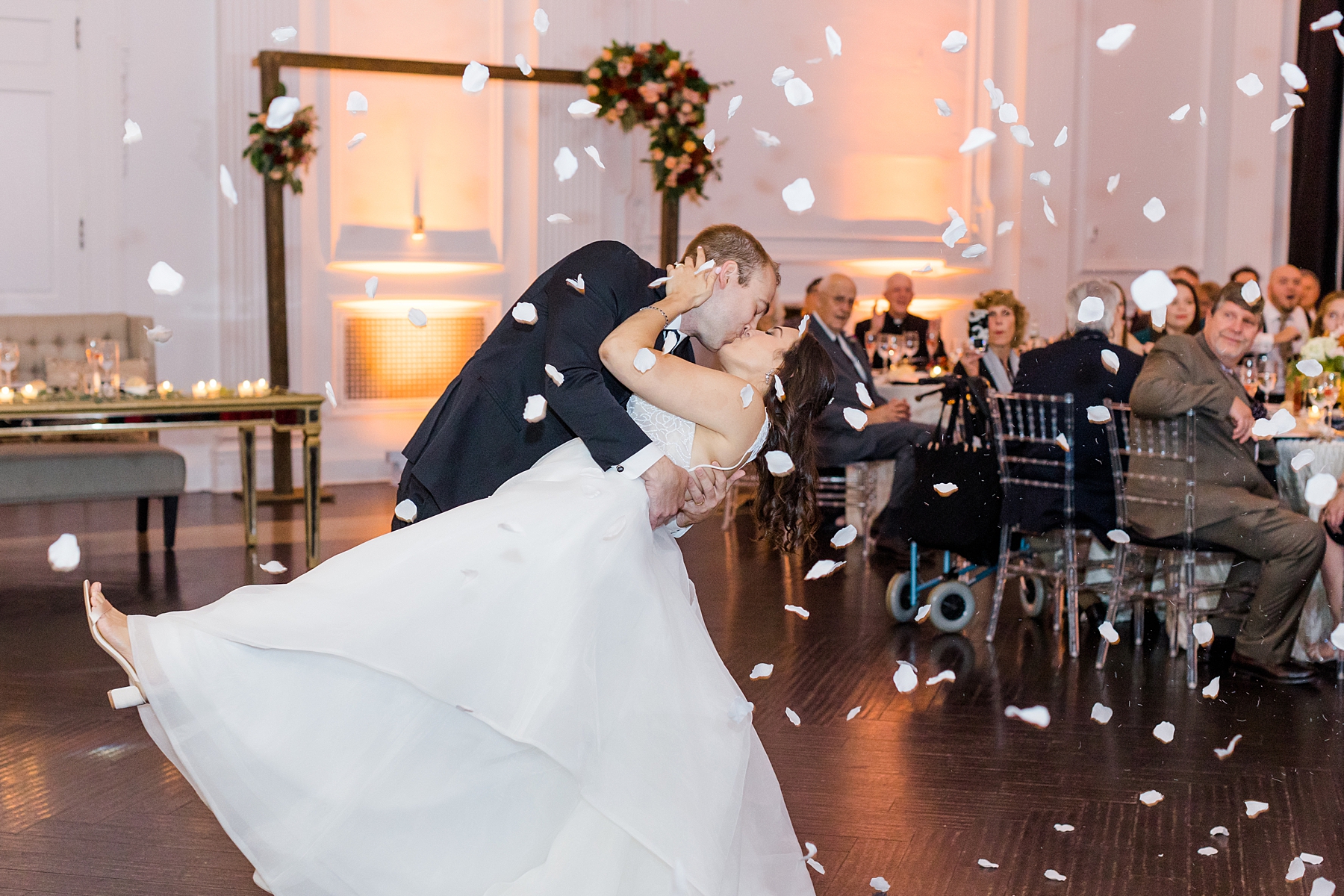 newlyweds kiss on the dance floor surrounded by flower petals