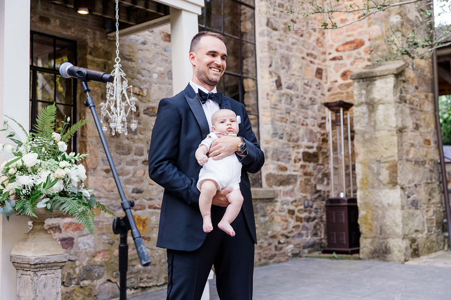 groom holding infant son at wedding ceremony